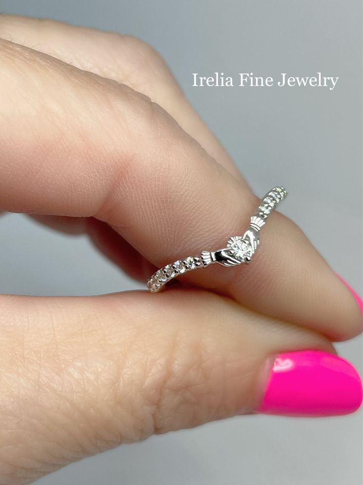 a woman's hand with a pink manicured nail polish and a diamond ring