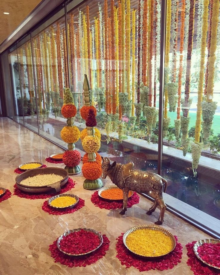 an animal statue sitting on top of a table filled with flowers and other decorations in front of a window