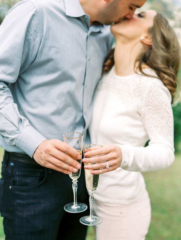 a man and woman kissing while holding champagne glasses