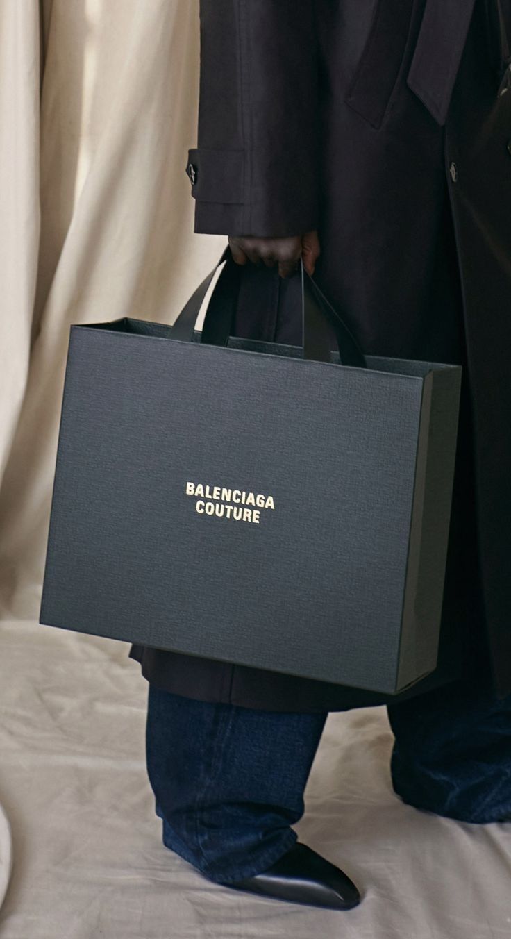 a man holding a black bag with the word balncicaa couture on it