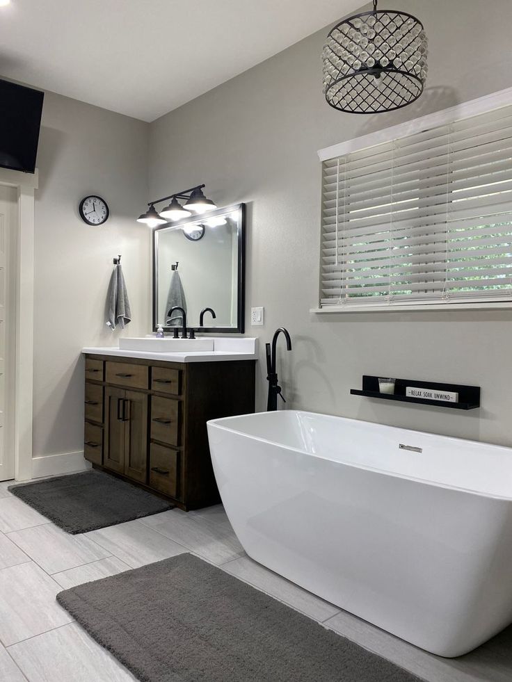 a white bath tub sitting under a bathroom mirror