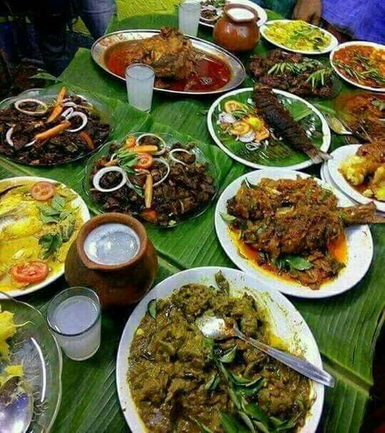 a large table full of food and drinks on top of a leafy green table cloth