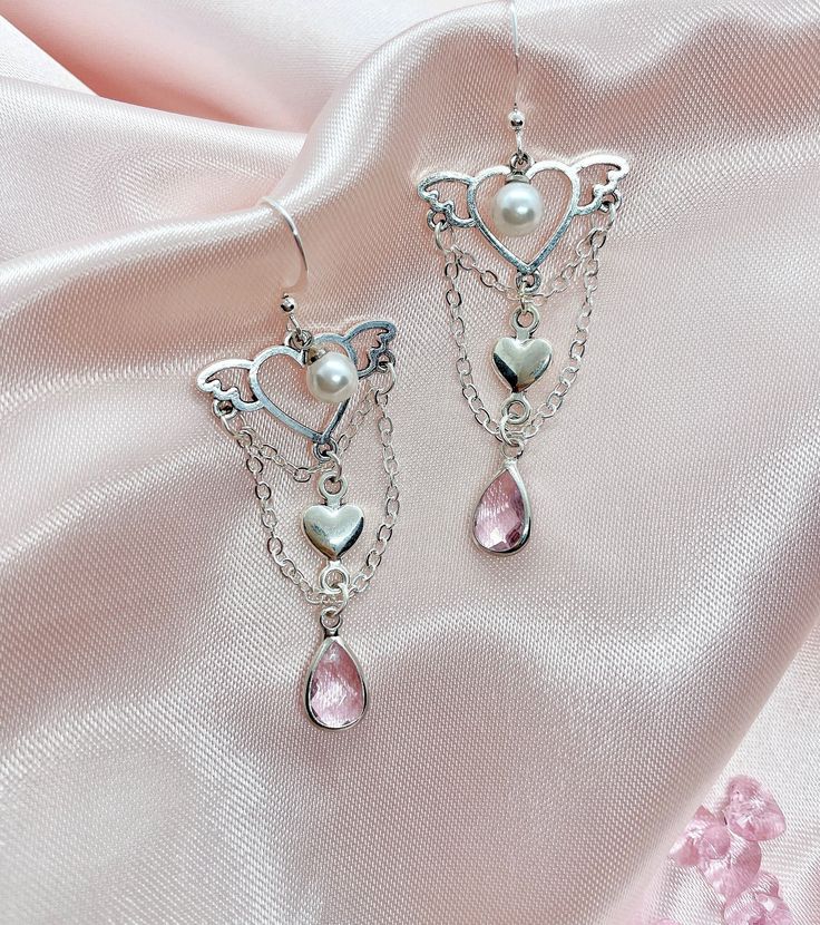 A pair of beautiful silver earrings. ☆ Ear hook/wire attachment ☆ Symmetrical style ☆ Adorned with pearls and pastel pink gems with silver chain embellishment ☆ Longest drop measures approx 5 cm from the ear hook attachment ☆ Plated mixed metal (zinc alloy, brass etc); may not be suitable for those with metal allergies ☆ Comes with a flower-shaped clear rubber ear hook stopper ☆ Handmade/hand assembled product so there may be some variations from the image shown For  a non-pierced version (ear s Pink Feminine Dangle Pearl Earrings, Pink Pearl Drop Earrings In Sterling Silver, Delicate Pink Dangle Pearl Earrings, Silver Chandelier Earrings With Dangling Charms As Gift, Pink Sterling Silver Pearl Earrings For Pierced Ears, Pink Sterling Silver Drop Pearl Earrings, Pink Dangling Charms Drop Earrings, Pink Drop Earrings With Dangling Charms, Silver Pearl Heart Earrings