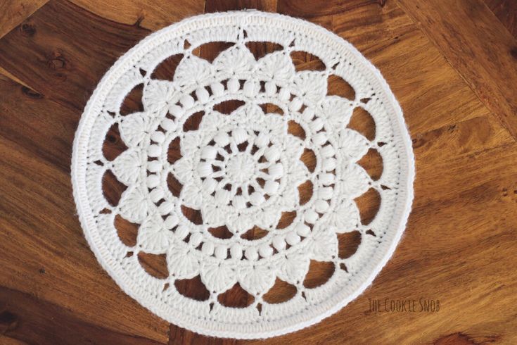 a white crocheted doily sitting on top of a wooden floor