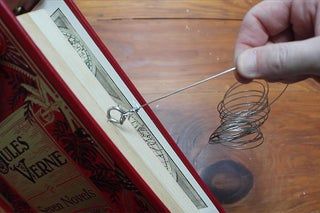 a person holding a wire in front of an open book