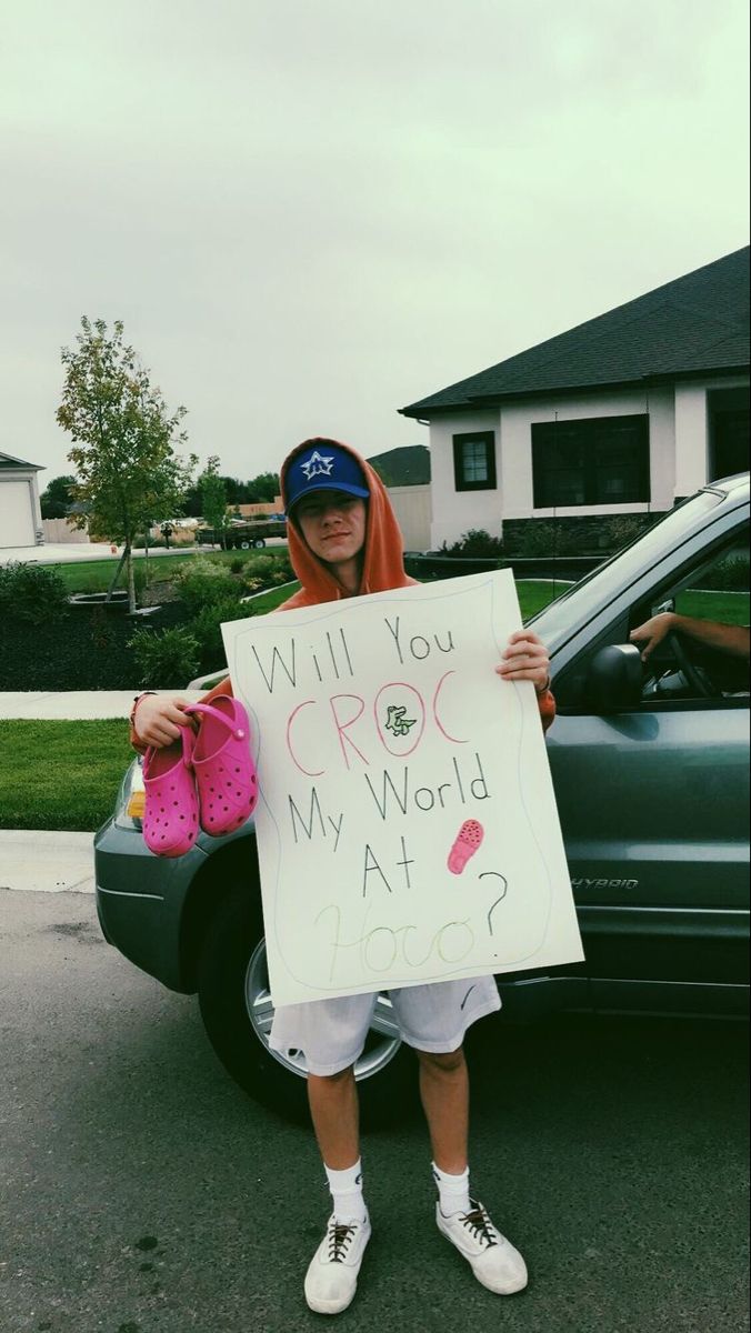 a person standing in front of a car holding a sign