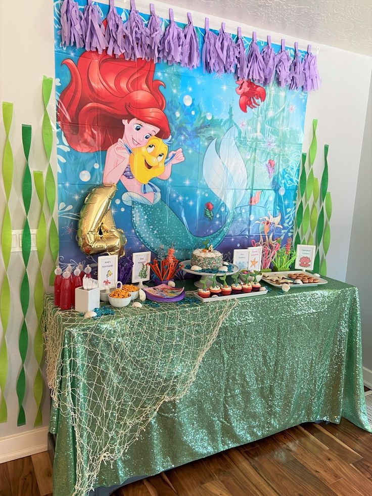 the little mermaid birthday party table is set up with an underseal backdrop and decorations