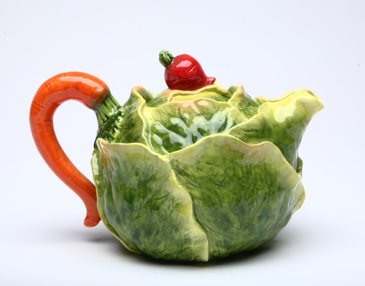 a ceramic teapot shaped like a leafy plant with a red pepper on top