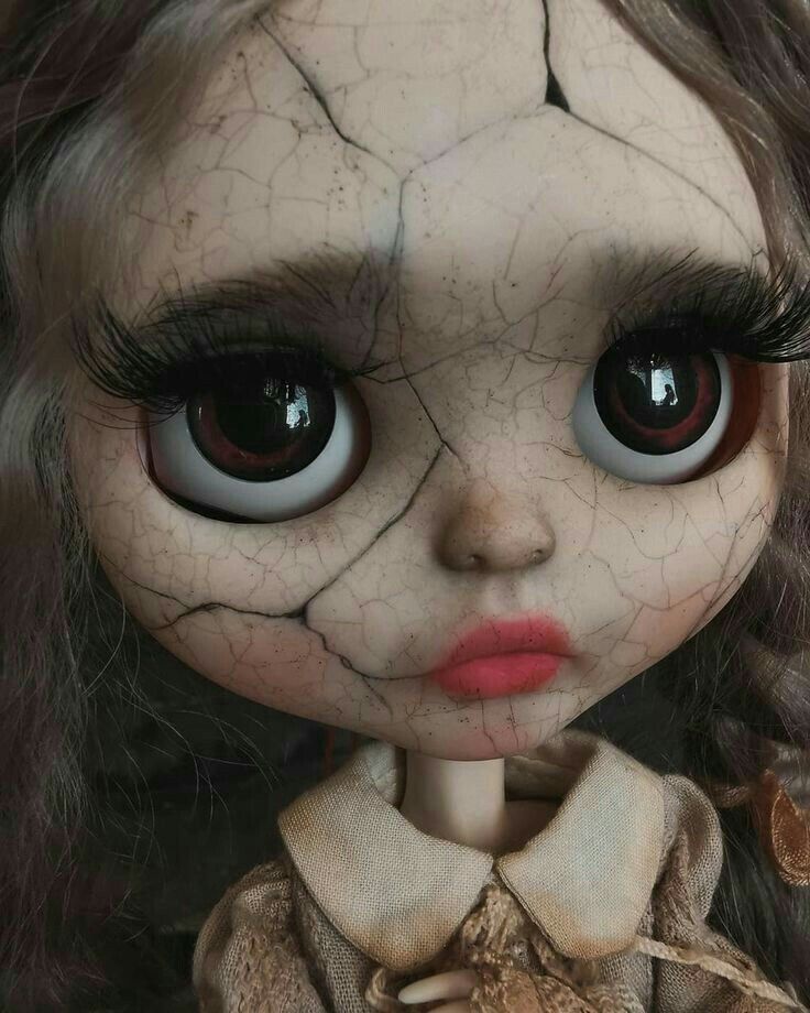 a doll with long hair and big eyes wearing a brown dress is looking at the camera