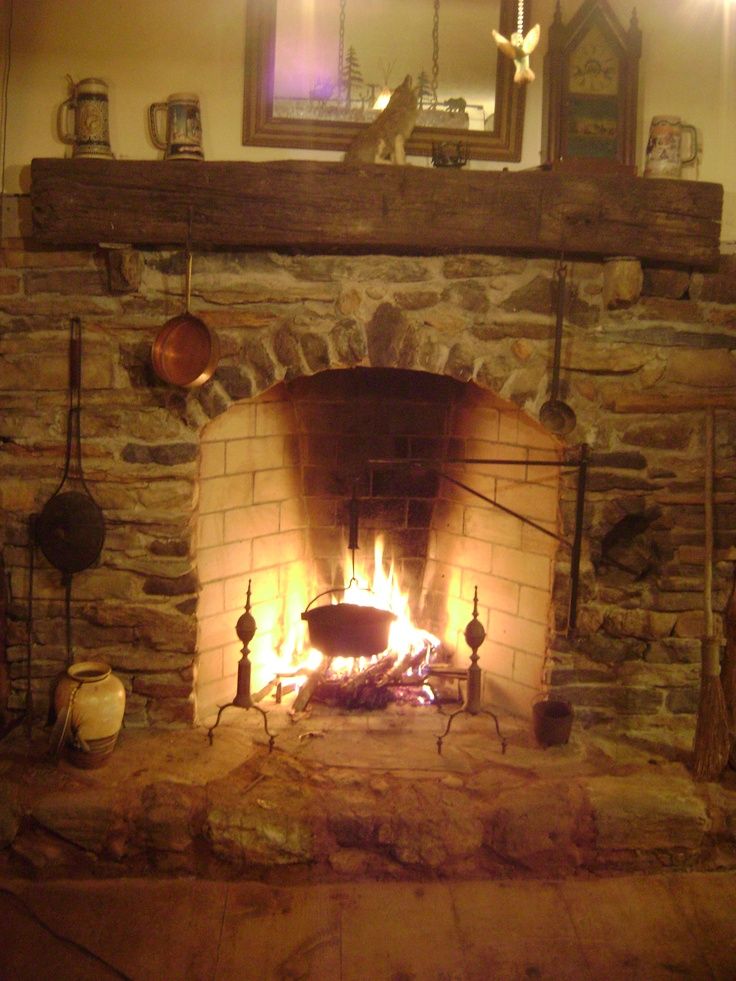 a fire in a fireplace with pots and pans on the mantle