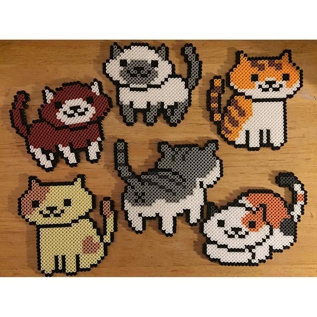 cross stitch cats and kittens on a wooden surface