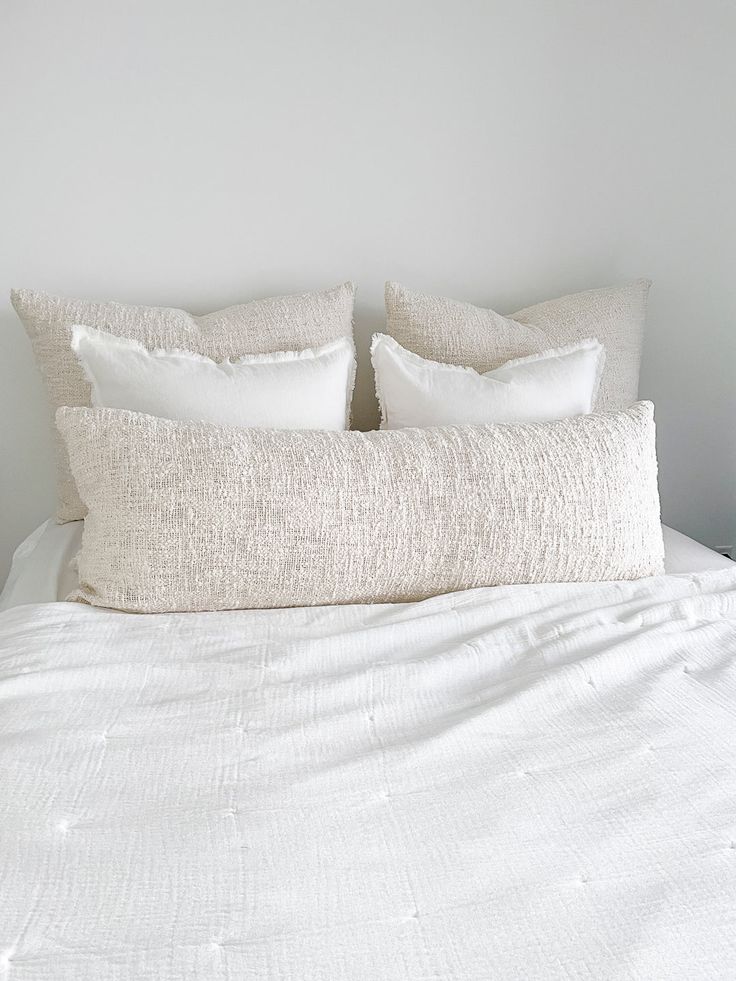 a white bed with two pillows on top of it