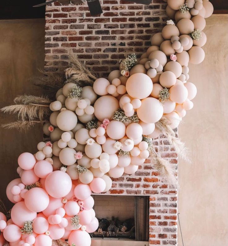 balloons are hanging from the ceiling in front of a brick wall with plants on it