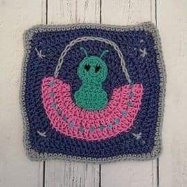 a crocheted square with a green and pink frog on it's back