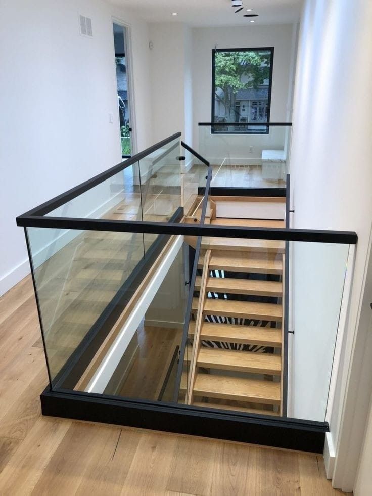 an empty room with wooden stairs and glass railing