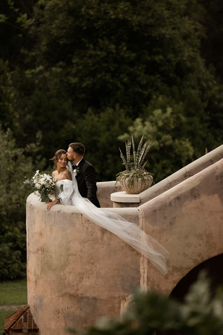 the bride and groom are posing for pictures on the stairs at their outdoor wedding venue