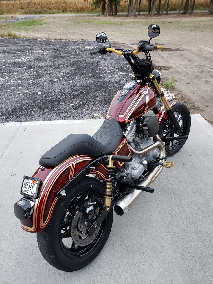 a red and black motorcycle parked on top of a parking lot next to a field