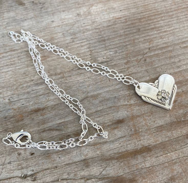 This gorgeous upcycled spoon heart necklace was made by marrying the ends of two silverplate spoon handles. The heart pendant was then adorned with a rhinestone flower for a little pizazz. Rhinestone flower is from a vintage rhinestone earring. The chain is a lovely loop chain in a silverplate finish. We do not cast/mold any of our designs, they are all handmade, one-of-a-kind creations. Manufacturer: William Rogers Pattern: Hiawatha Year: 1939Size/Dimensions: Pendant is ~1"w x ~1". Chain is ~22 One Of A Kind Heart Shaped Vintage Jewelry, One-of-a-kind Heart-shaped Vintage Jewelry, One Of A Kind Heart Jewelry For Anniversary, Elegant Stamped Heart-shaped Jewelry, Elegant Heart-shaped Necklace, Vintage Charm Pendant Jewelry For Anniversary Gift, Nickel-free Heart Pendant For Wedding, Nickel-free Heart Pendant Wedding Jewelry, Vintage Pendant Jewelry For Anniversary Gift