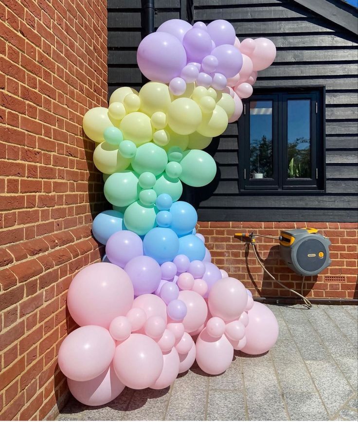 there is a large number of balloons on the side of a building with a hose attached to it