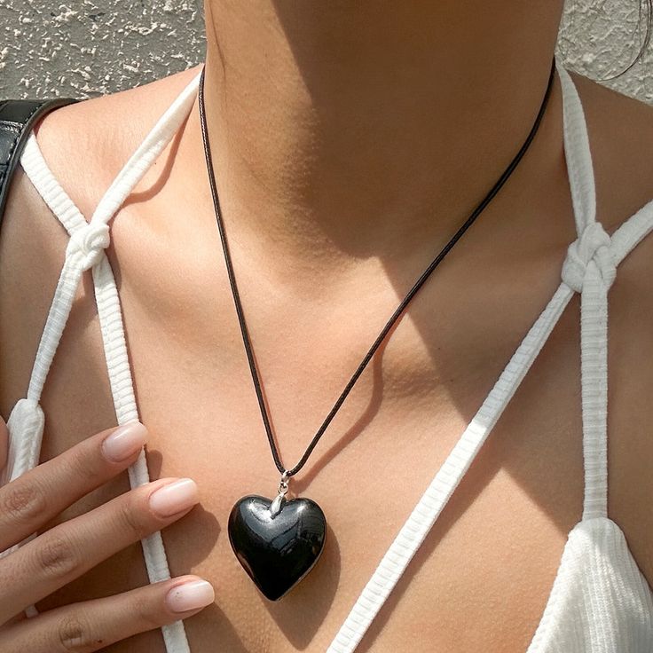 This charming pendant necklace features a sleek black leather cord and a heart-shaped pendant. The simple yet elegant design makes it a versatile accessory that can be worn with a variety of outfits. Perfect for adding a touch of romance to any look. Shop now for a stylish addition to your jewelry collection. Trendy Black Jewelry With Adjustable Cord, Trendy Adjustable Heart Pendant Necklace, Chic Adjustable Heart-shaped Necklace, Adjustable Trendy Heart Pendant Necklace, Black Heart-shaped Jewelry, Chic Heart-shaped Adjustable Necklace, Trendy Black Pendant Necklace, Chic Black Heart-shaped Jewelry, Trendy Black Heart Necklace For Gift