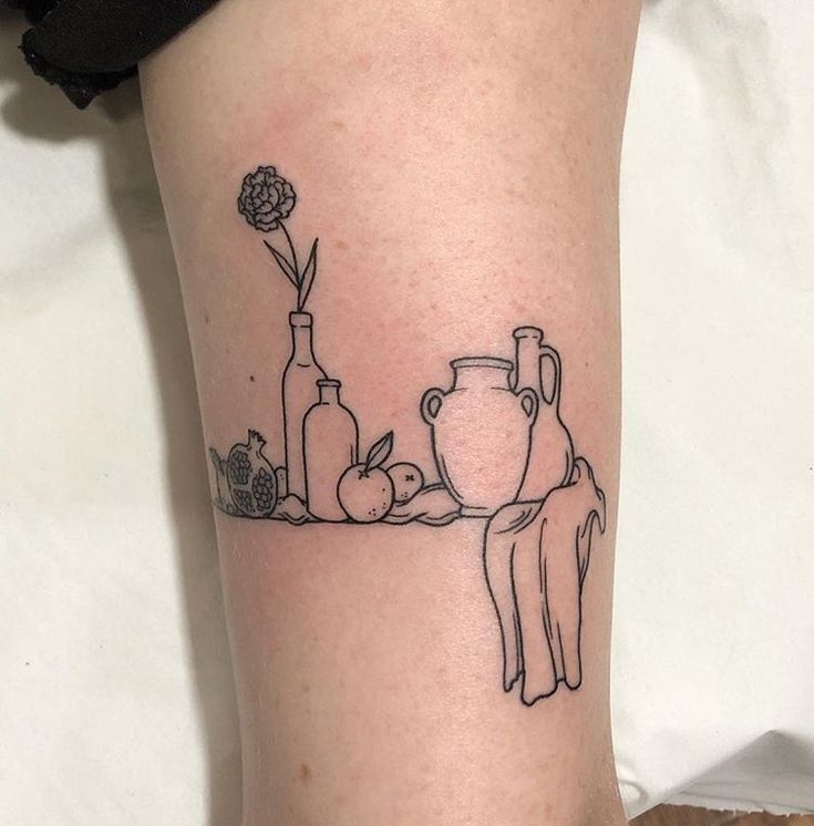 a woman's leg with a line drawing of vases and apples on it