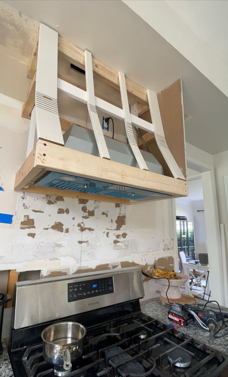 a stove top oven sitting inside of a kitchen next to a wall under construction work