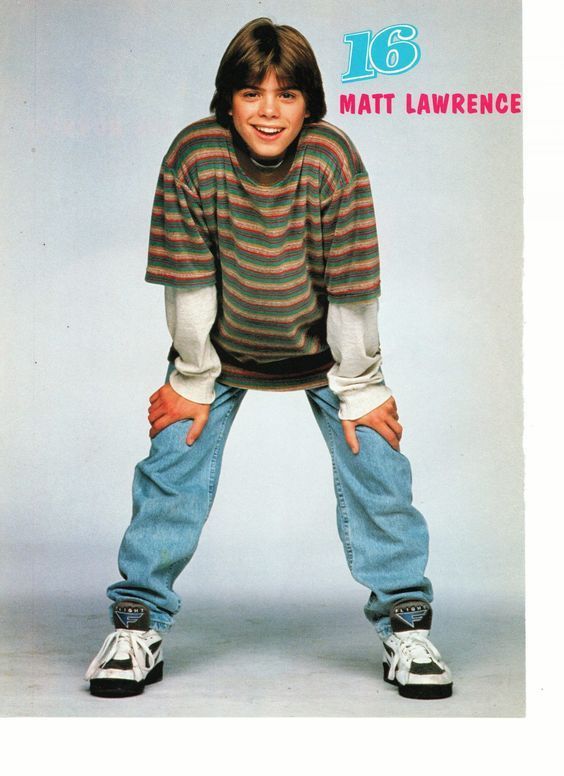 a young boy wearing jeans and a striped shirt with his hands on his hips, posing for the camera