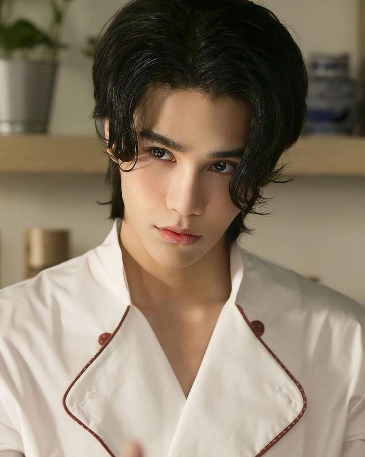 a young man with black hair wearing a white shirt and red trim around his collar