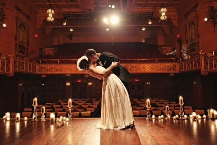 a man and woman dance in front of an auditorium full of candles on the floor