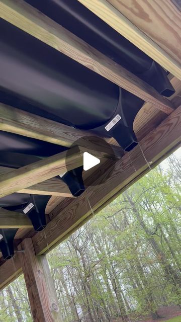 the underside of a wooden structure with pipes attached to it and trees in the background