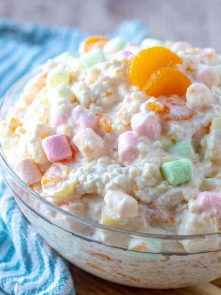 a bowl filled with cereal and marshmallows on top of a wooden table