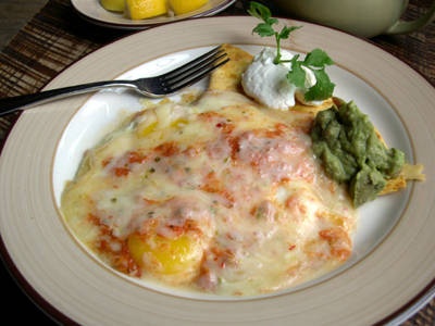 a white plate topped with lasagna next to a bowl of guacamole