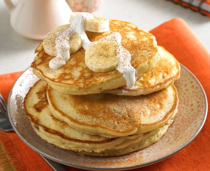 a stack of pancakes topped with bananas and powdered sugar