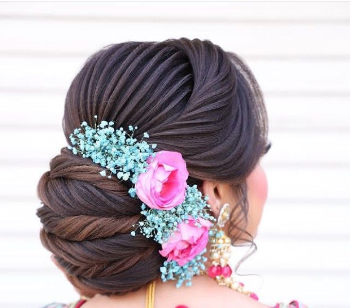 the back of a woman's head with flowers in her hair and jewelry on it