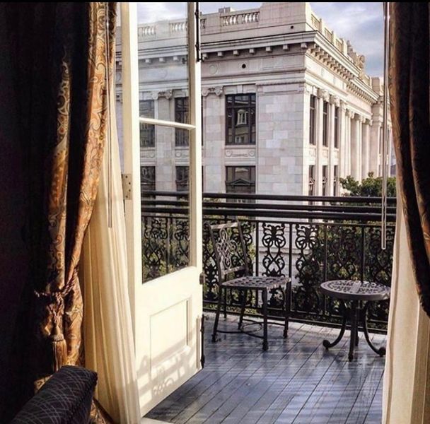 an open door leading to a balcony with tables and chairs on the other side of it