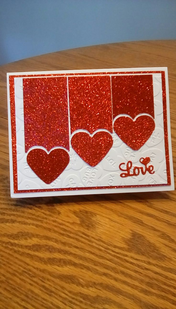 a card with three hearts and the word love on it, sitting on a table