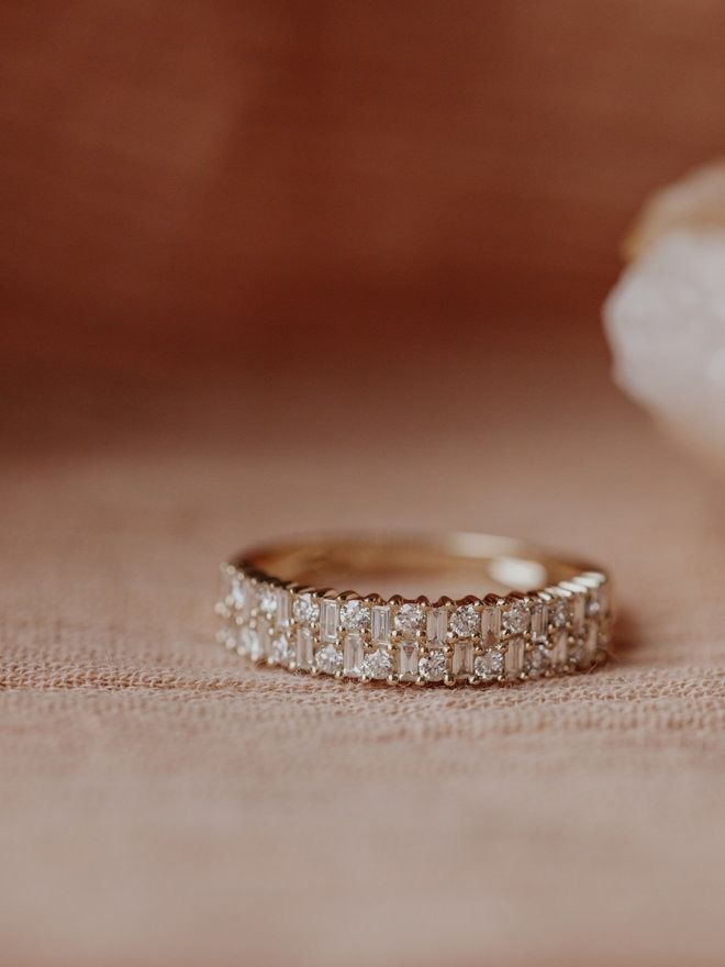 two wedding bands sitting on top of a pink cloth next to a white flower in the background