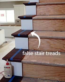 the stairs are painted white and brown with blue tape on them, as well as an arrow pointing to false stair treads