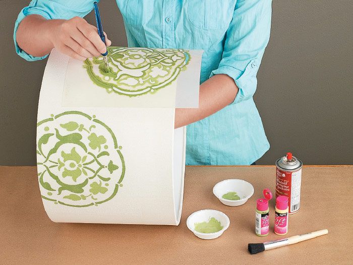 a woman is painting on a bag with green paint and some other crafting supplies