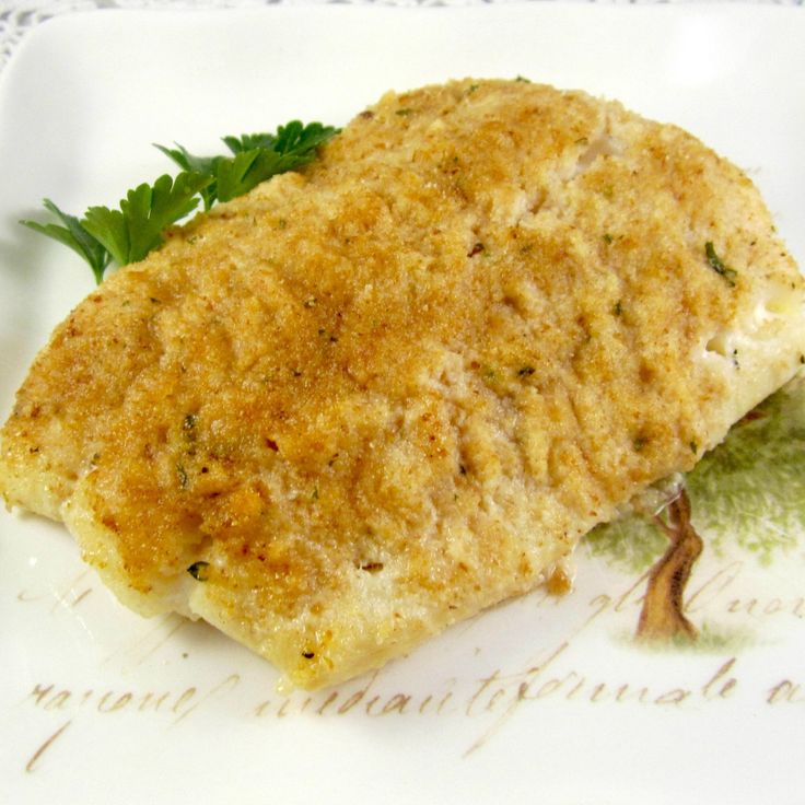 a piece of fish on a plate with parsley garnish and some type of sauce