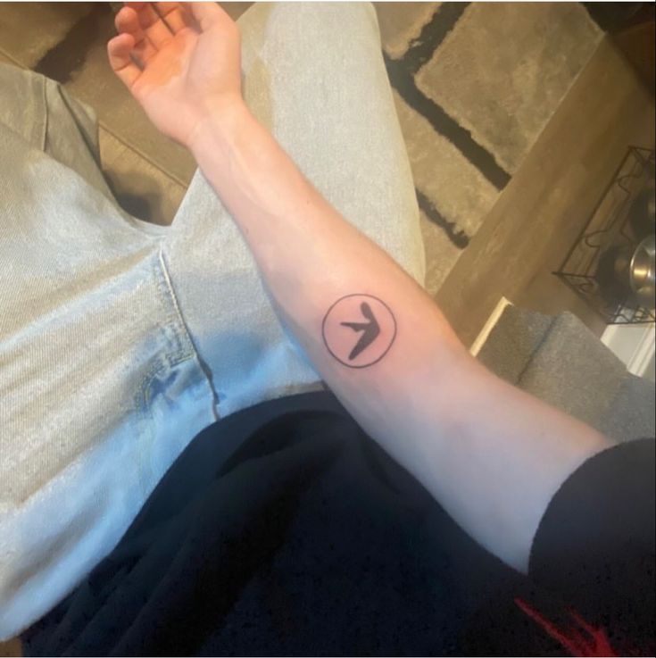 a person's arm with an arrow tattoo on the left side of their arm