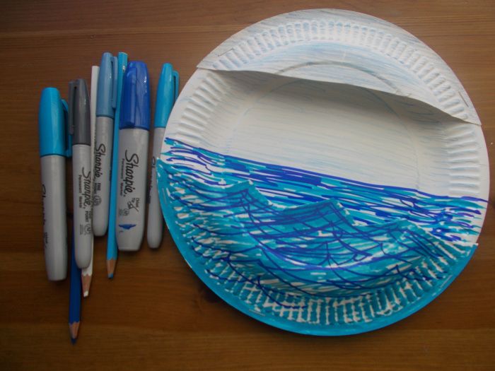 a paper plate with blue and white designs on it, next to markers for drawing