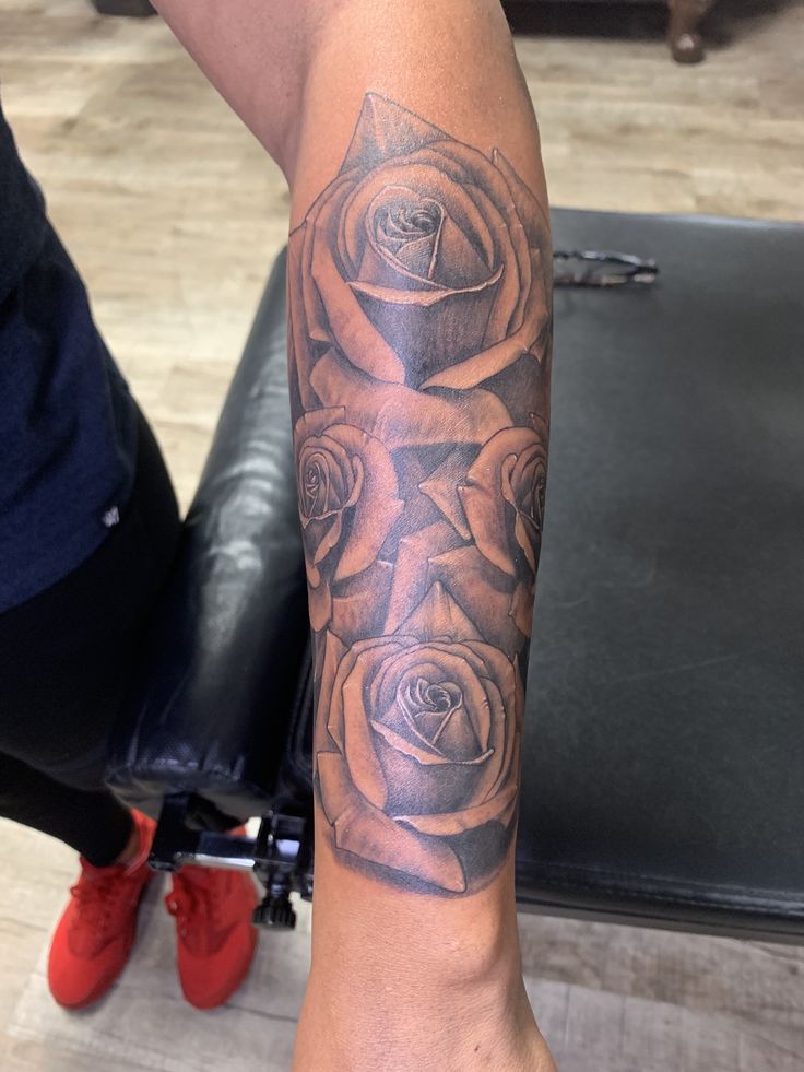 a woman's arm with roses on it and an arrow in the middle is shown