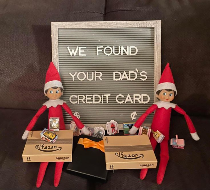 two elfs are sitting next to each other near a sign that says we found your dad's credit card