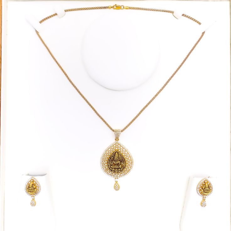 Embrace luxury with our Impressive Lakshmi 22k Gold CZ Pendant Set. Crafted from 14.5g of pure 22k gold, adorned with dazzling Cubic Zirconia. The pendant boasts a 2.2" length, complemented by matching 1" earrings with secure screw backs. Elevate your style with this exquisite 3-piece set. PRODUCT DETAILS Gold Purity(karat): 22k Item Weight(grams): 14.5 Item Finish: Yellow Gold Stone: Cubic Zirconia Pendant Length: 2.2" Matching Earrings: Included Earring Length: 1" Earring Post: Screw Back Numb 22k Yellow Gold Jewelry Sets For Puja, Traditional Jewelry Sets With Diamond Accents, Elegant 22k Gold Jewelry Sets For Puja, Intricate Yellow Gold Diamond Necklace Gift, Gold Diamond Temple Necklace For Wedding, Festive Gold Temple Necklace With Diamonds, Traditional Yellow Gold Diamond Necklace Gift, Festive Gold Diamond Temple Necklace, Gold Bollywood Jewelry Sets With Cubic Zirconia