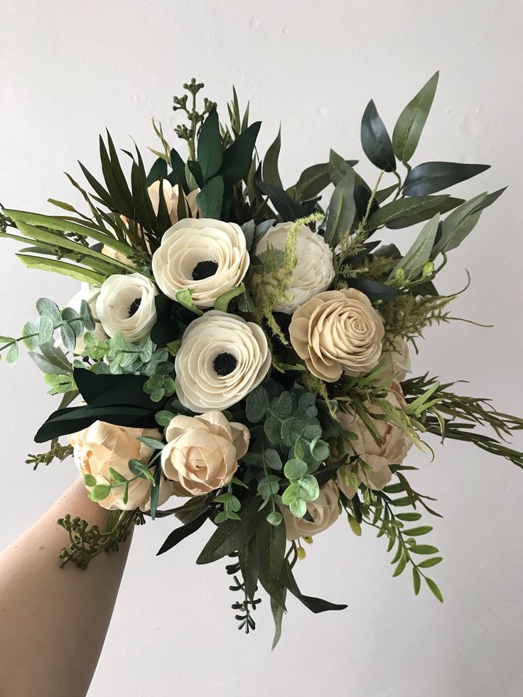 a bouquet of white and green flowers in someone's hand