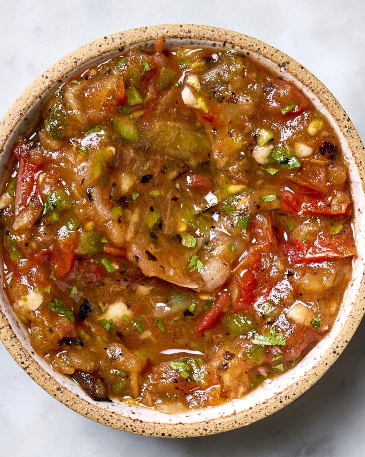 a bowl filled with meat and vegetables on top of a white countertop next to a spoon