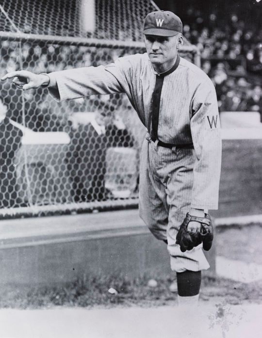 an old black and white photo of a baseball player stretching his arm out to catch the ball