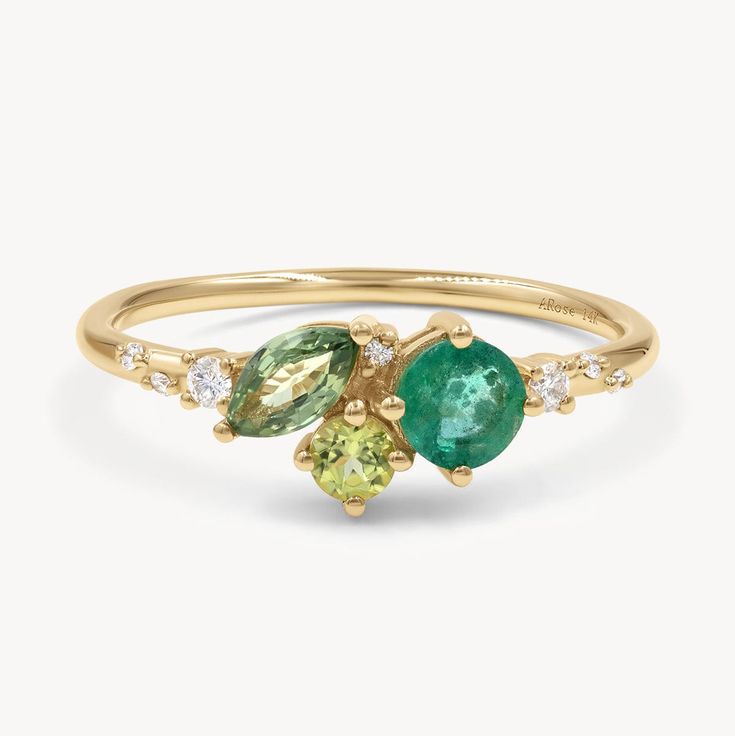 a yellow gold ring with two green and white stones on the side, set against a white background