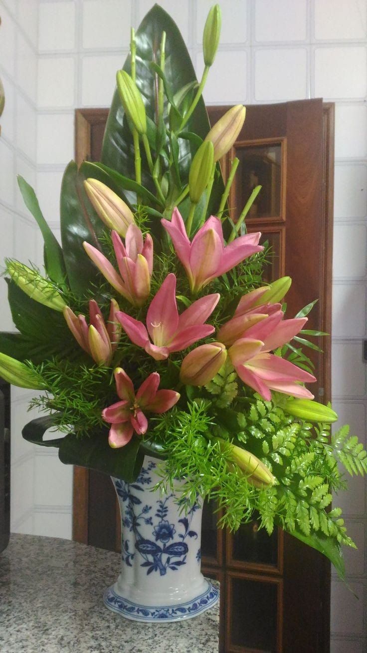 a blue and white vase filled with flowers on top of a marble counter next to a mirror